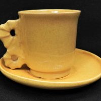 Klytie-Pate-Australian-Pottery-Cup-Saucer-Yellow-glaze-with-Sea-Horse-like-Handle-incised-signature-to-bases-small-chip-to-base-of-cup-Sold-for-93-2021