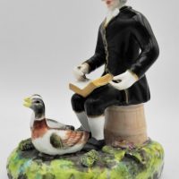 19th-C-Derby-porcelain-figurine-gent-sitting-on-barrel-outside-with-book-2-ducks-Stevenson-and-Hancock-mark-14cms-H-af-pen-missing-from-hand-Sold-for-99-2021