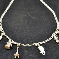 Long silver necklace with 8 charms - Coronation carriage, Eiffel tower, windmill, clog, figures etc - Sold for $31 - 2017