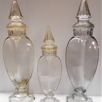 3 x c1900 Tall pressed Tiffin Dakota show Glass Apothecary jars with pointed lids Pair 54cm tall & smaller one 41cm - Sold for $310 - 2018