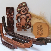 Group of carved wooden items incl Maori Longboats, Tikki plaques, shell with woven fringe etc - Sold for $37 - 2018