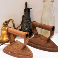Group lot incl metal powder flask, milk bottle, brass bell and 2 x vintage sad irons - Sold for $31 - 2018