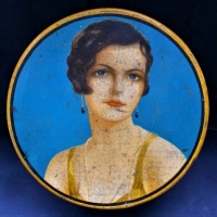 1920s - 30s Art Deco round tin with image of a pretty girl with a short bob and wearing drop earrings - Sold for $75 - 2018