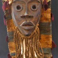 Carved wooden West African black tribal mask with central ridge to forehead, sackng headress and fringed tassel beard - Sold for $323 - 2019