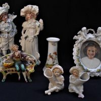 Group of c1910 china including Staffordshire Boy and girl figurines, German bisque photo frame and bud vases etc - Sold for $37 - 2019