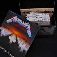 Small group lot Metallica merchandise incl 1986 LP vinyl record Metallica - Master Of Puppets (WEA) album and cased Live St VHS set - Sold for $50 - 2019