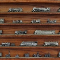 Wooden display case with assorted miniature metal train models on tracks - Sold for $87 - 2016