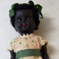 1950's English Small black plastic girl DOLL - wearing ribbons in hair & original dress - 18cms long - Sold for $85 - 2014