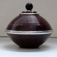 MOTTLED BROWN BAKELITE LIDDED CONTAINER with chrome rim to centre and top, round dark know to top - Sold for $79 - 2013