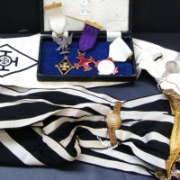 Group lot Masonic sashes and medals, regalia  inc - eagle medal, black and white striped sash with heavy gilt fringe, etc - Sold for $37