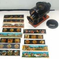Victorian tin & brass SLIDE PROJECTOR inc box of fantastic colour slides depicting gentleman riding forest animals, sailing ships, circus acts, market - Sold for $73 - 2014