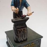 Heavy reproduction cast iron money bank - blacksmith w anvil, Bank on John Deere Quality 24cm - Sold for $85 - 2015