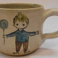 Sylva Halpern Australian  pottery mug with cream ground and hpainted image of a child holding a balloon to front and flowers to back, signed to base,  - Sold for $35 - 2019